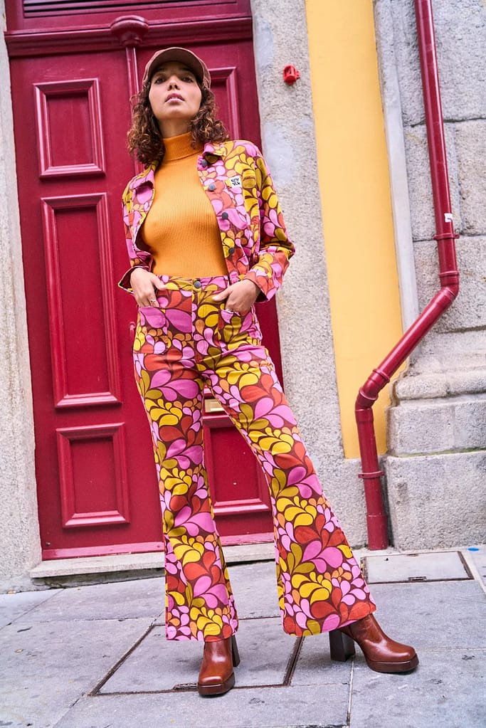 Model wears floral trouser and jacket co-ord in pink and orange by Lucy and Yak