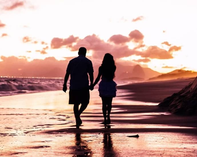 two people walking on a beach - photo by Edgar Chaparro Holiday Romance