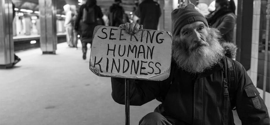 Photo of Homeless man holding a sign that says "Seeking Human Kindness"